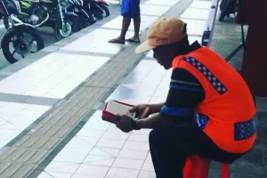 Tukang parkir ini jagain kendaraan sambil baca Alquran, bikin salut